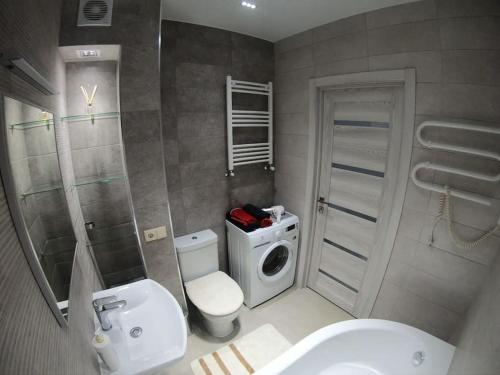 a bathroom with a toilet sink and a washing machine at Новая, уютная квартира по ул. Grenoble 120/10 in Chişinău