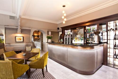 a bar in a restaurant with a table and chairs at Windermere Hillthwaite Hotel in Windermere