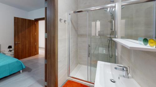 y baño con ducha y lavabo blanco. en Modern 3-bedroom apartment Pieta, en Tal-Pietà