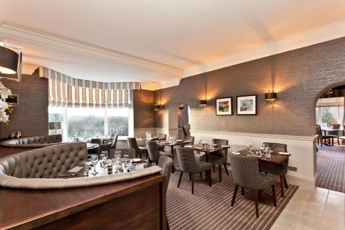 a restaurant with tables and chairs and a bar at Windermere Hillthwaite Hotel in Windermere