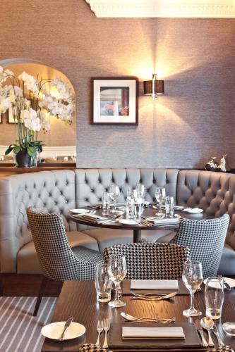 a dining room with tables and chairs and a wall with a picture at Windermere Hillthwaite Hotel in Windermere