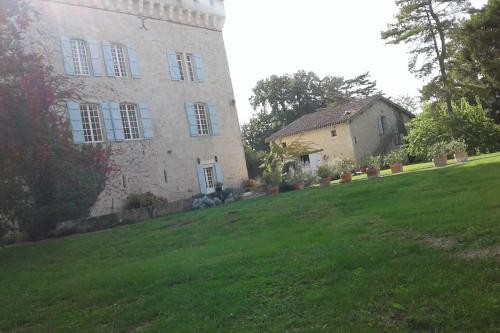 a building on a grassy hill next to a house at Château Déhès Gazaupouy 1 chambre d'hôte et 1 Gite in Gazaupouy