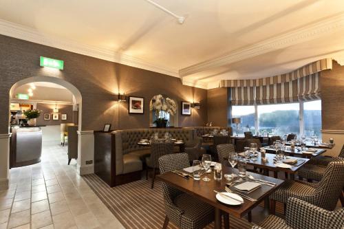 a restaurant with tables and chairs and a bar at Windermere Hillthwaite Hotel in Windermere