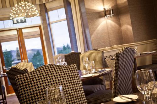 a restaurant with chairs and tables with wine glasses at Windermere Hillthwaite Hotel in Windermere