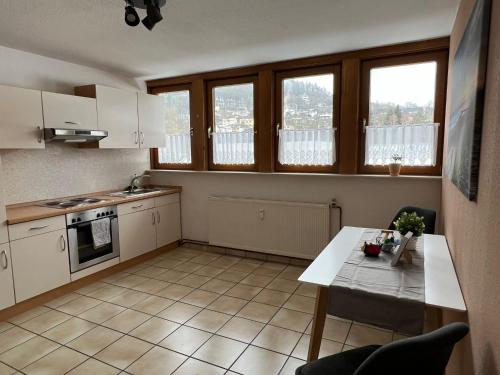 eine Küche mit weißen Schränken und einem Tisch darin in der Unterkunft Ferienwohnung Schneider mit Balkon in Bad Laasphe
