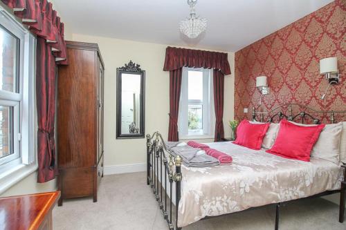 a bedroom with a large bed with red pillows at The Beach House Luxury Rooms Weston Super Mare in Weston-super-Mare