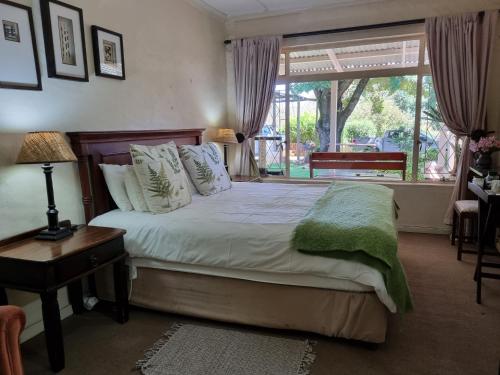 1 dormitorio con cama y ventana grande en Yellowwood Cottage, en Himeville