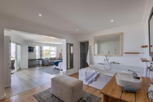 a large white bathroom with a tub and a chair at Endless Summer Villa in Plettenberg Bay