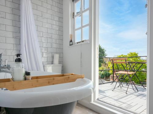 ein weißes Bad mit einer Badewanne und einem Balkon in der Unterkunft Pass the Keys The Hay Loft in Canterbury