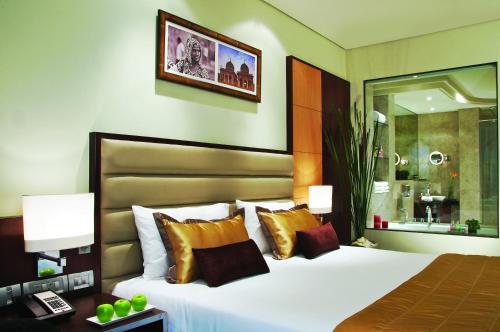 a bedroom with a large white bed with gold pillows at Vivanta Hyderabad, Begumpet in Hyderabad