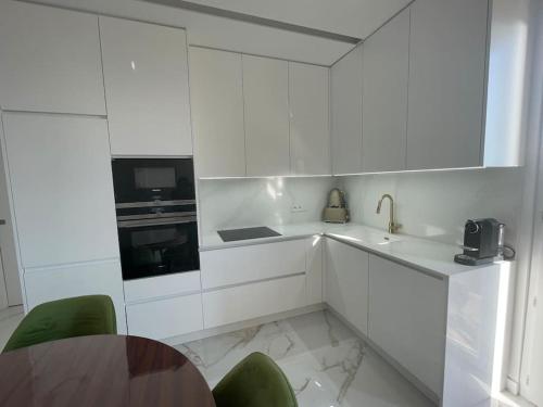 Biała kuchnia z białymi szafkami i zielonymi krzesłami w obiekcie Luxueux appartement aux portes de Monaco - CAP D AIL w mieście Cap d'Ail