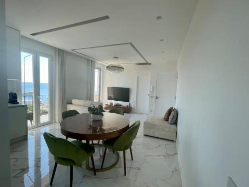 salon ze stołem i zielonymi krzesłami w obiekcie Luxueux appartement aux portes de Monaco - CAP D AIL w mieście Cap d'Ail
