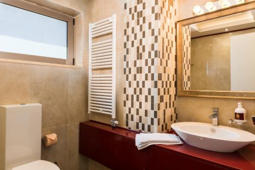 W łazience znajduje się umywalka, lustro i toaleta. w obiekcie Angel Hill Villa w mieście Xirokámbion