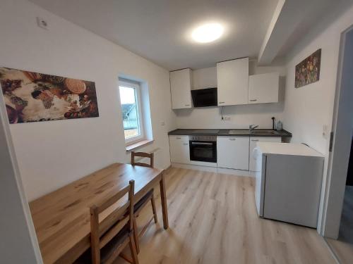 a kitchen with white cabinets and a wooden table at Ferienappartment & Ferienwohnung Banfetal in Bad Laasphe