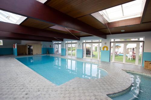 a large swimming pool in a building with windows at Beausite Hotel in Grouville