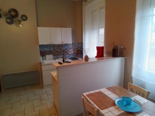 a kitchen with a counter and a table in a room at Charmant studio centre bourg in Woincourt
