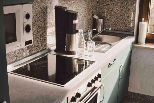 a kitchen counter with a sink and a microwave at Fritz' FeWo in Veldenz