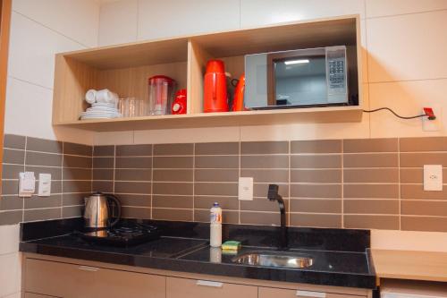 a kitchen with a sink and a microwave at Chocolate com pimenta Edifício - Praia do Bessa in João Pessoa