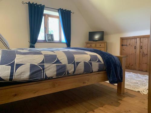 Upper Home Farm في Plaish: غرفة نوم بسرير والستائر زرقاء وتلفزيون