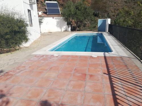 a swimming pool with a tile floor and a house at Casa Antonia in Algarrobo
