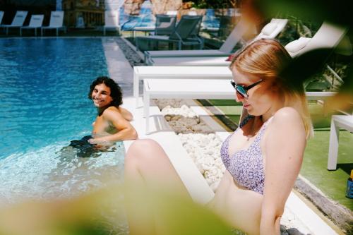 a man and a woman sitting in a swimming pool at Campus Hub Malta in Msida