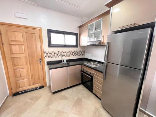 a kitchen with a stainless steel refrigerator and a door at Beachfront Apartment in Imi Mikki