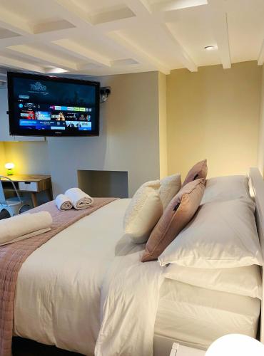 1 dormitorio con 1 cama con almohadas y TV en la pared en Cosy Central Hideaway en St. Leonards