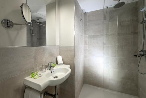 ein weißes Bad mit einem Waschbecken und einer Dusche in der Unterkunft Apartamentos Hesperia Bristol Playa in Corralejo