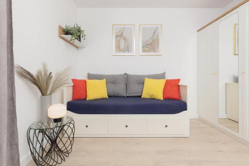 a room with a bench with colorful pillows on it at Warsaw Piaseczno Peaceful Apartment Cichej Łąki by Renters in Piaseczno