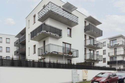 apartamentowiec z balkonami i samochód zaparkowany przed budynkiem w obiekcie Warsaw Piaseczno Peaceful Apartment Cichej Łąki by Renters w Piasecznie