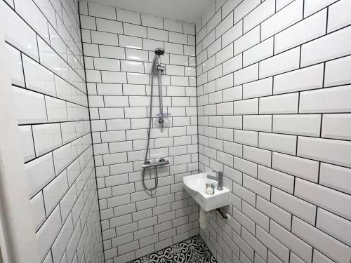 a white tiled bathroom with a sink and a shower at Flat 4, 10 St John's in Bournemouth
