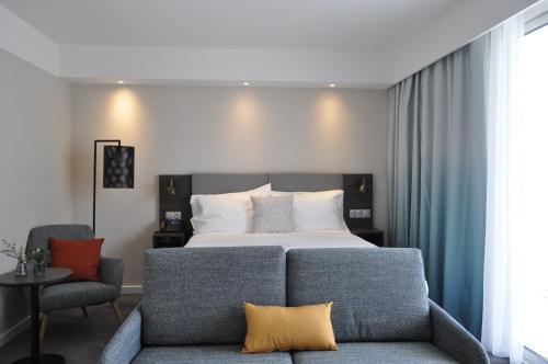 a bedroom with a bed and a couch and a chair at Holiday Inn - Bordeaux-Merignac by IHG in Mérignac