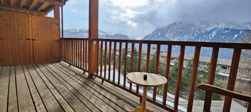 a wooden porch with a table on a balcony with mountains at Hostdomus - Sansicario R21 in Cesana Torinese