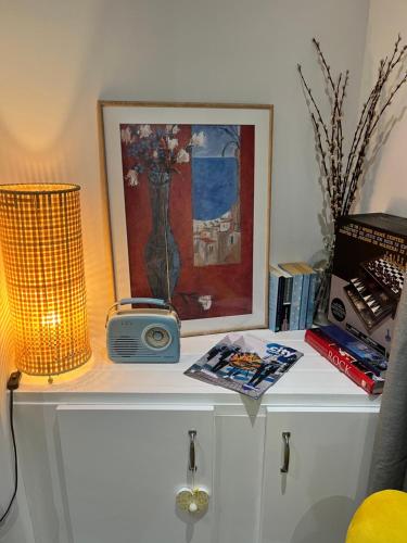 a table with a clock and a picture and a lamp at Stay-K-Belfast Cosy house 10 mins from city centre in Belfast