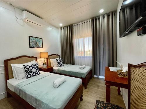 una camera d'albergo con 2 letti e una scrivania di Villa Lydia y Jose Heritage Hotel a Bayubay Sur