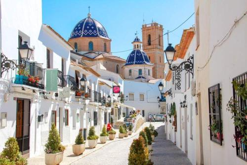 a street in a town with white buildings and blue domes at altea home centre one badroom in Altea
