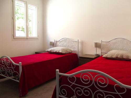 - une chambre avec 2 lits avec des draps rouges et une fenêtre dans l'établissement Les Grands Prés des Baronnies, à La Roche-sur-le-Buis