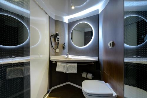 a bathroom with a toilet and a sink and a mirror at ibis München Parkstadt Schwabing in Munich
