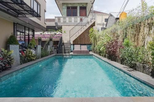 a swimming pool in the middle of a house at Taxa Uma Guest House in Kuta