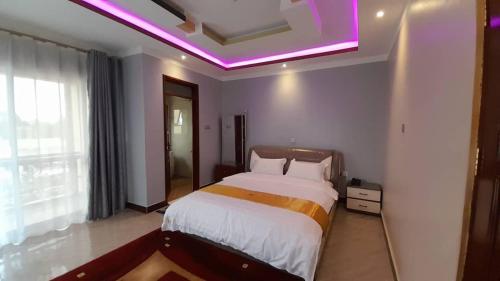 a bedroom with a large bed with a purple lighting at Das Berliner Hotel in Kampala