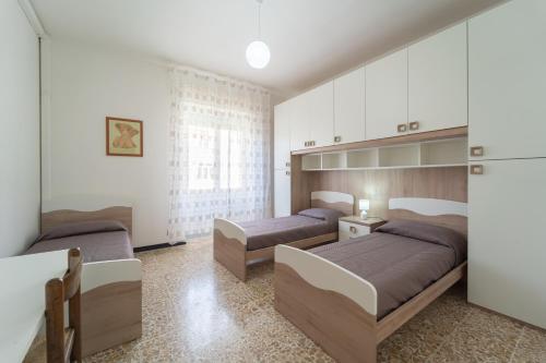 two beds in a bedroom with white cabinets at HAPPY HOME in Alghero