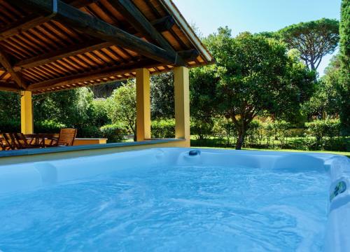 un bain à remous dans un jardin avec une pergola dans l'établissement Ville Di Villa Biserno, à San Vincenzo