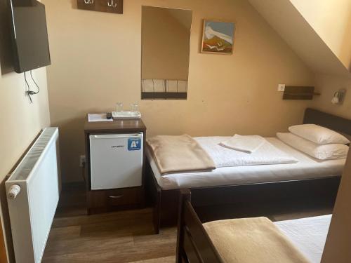 a small room with two beds and a tv at Kastélykert Fogadó in Szeged