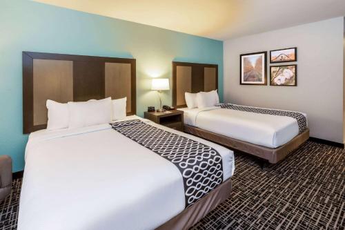 um quarto de hotel com duas camas e duas mesas em La Quinta by Wyndham Jonesboro em Jonesboro