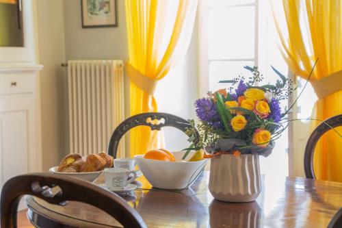a table with a vase of flowers and oranges on it at Casa Rossana - WelcHome in Cannobio