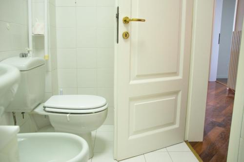 a white bathroom with a toilet and a door at Casa Rossana - WelcHome in Cannobio