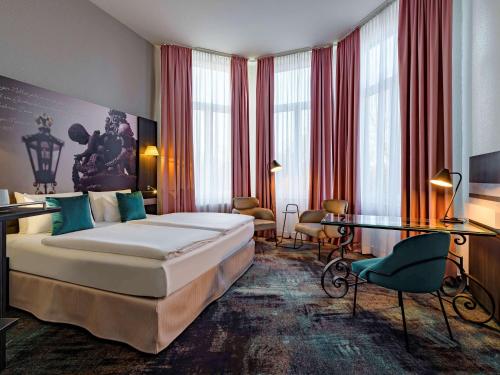 a hotel room with a bed and a desk at Mercure Hotel Hannover City in Hannover