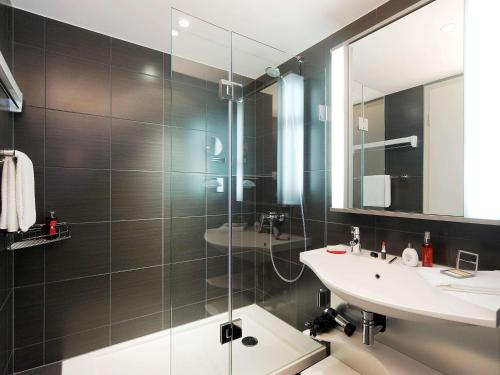 a bathroom with a glass shower and a sink at Aparthotel Adagio Muenchen City in Munich