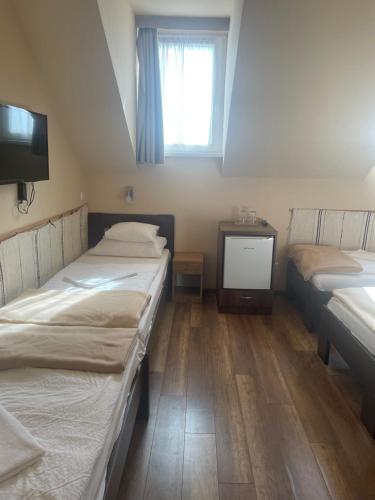 a room with two beds and a tv in it at Kastélykert Fogadó in Szeged