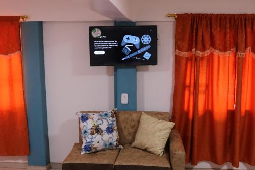 Habitación con sofá y TV en la pared. en Hospedaje Vacacional y Familiar Baños, en Baños